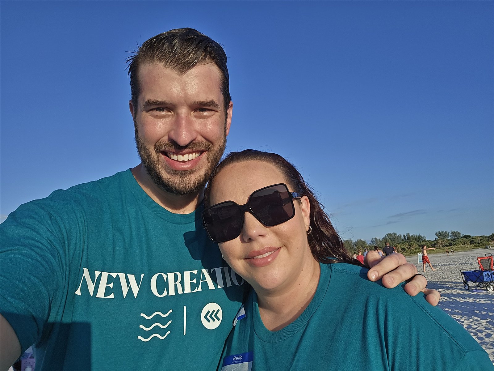 Greg and Amber on the beach after being baptized together, wearing New Creation shirts.